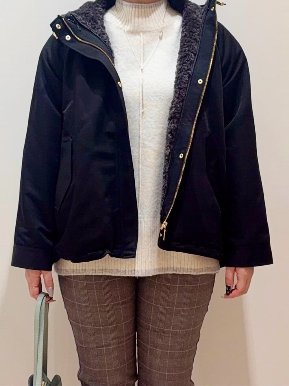 ブラック系のブルゾン、ホワイト系のニット/セーター、ベージュ系のその他パンツを着用したレディースの冬コーディネートの4枚目の写真
