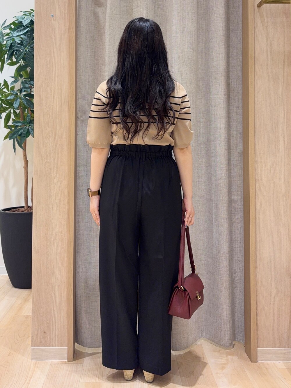 ベージュ系のニット/セーター、ブラック系のその他パンツ、レッド系のショルダーバッグを着用したレディースの夏コーディネートの3枚目の写真