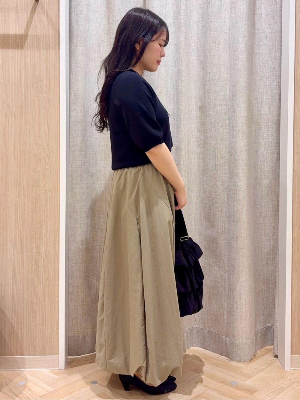 ブラック系のパンプス、グリーン系のスカート、グレー系のカーディガン/ボレロを着用したレディースの春コーディネートの2枚目の写真