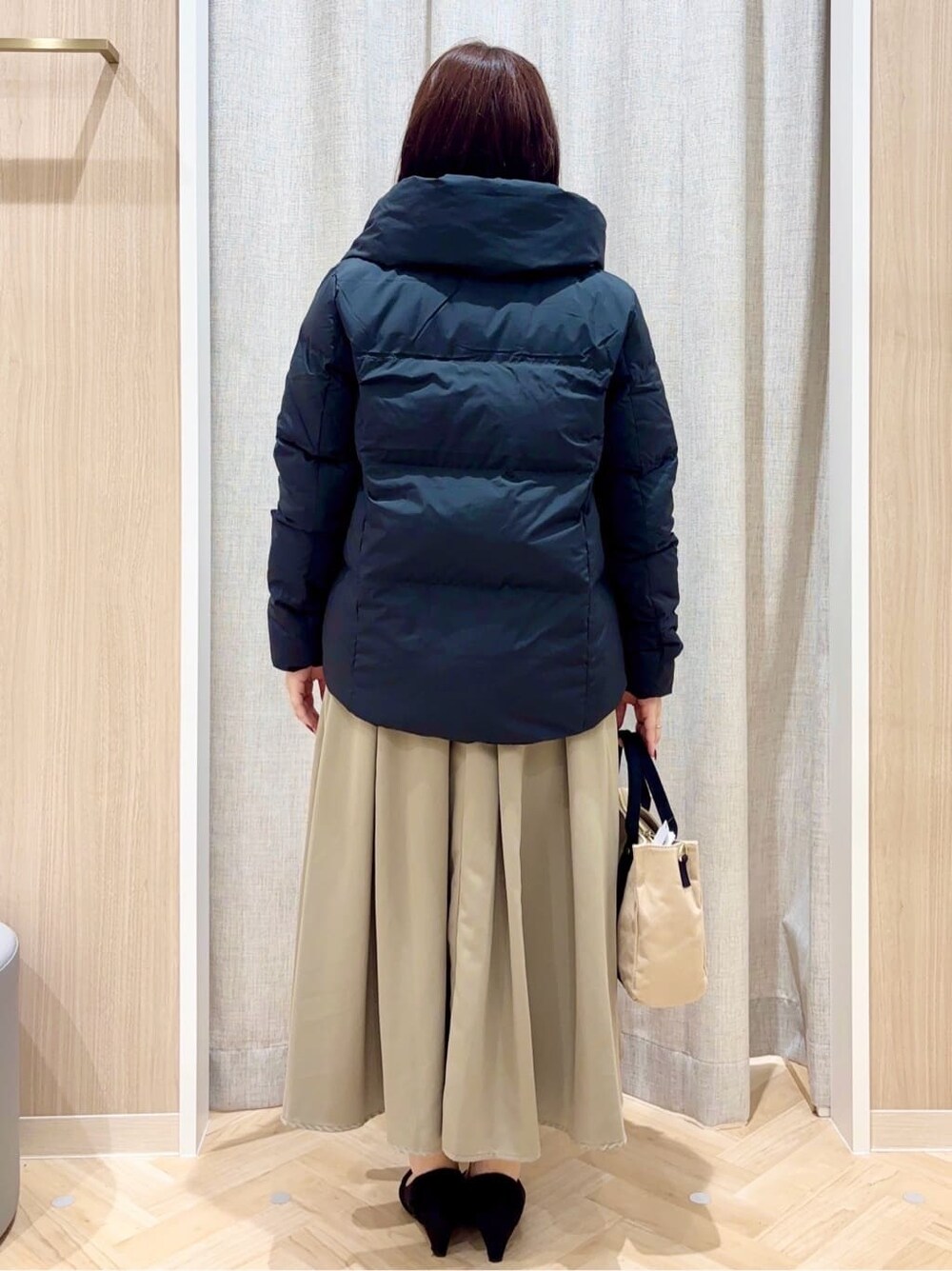 ベージュ系のニット/セーター、グリーン系のスカート、ブラック系のトートバッグを着用したレディースの冬コーディネートの3枚目の写真