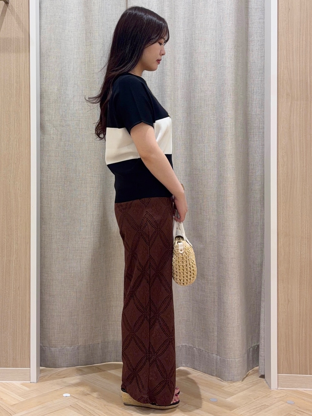 ブラック系のニット/セーター、ブラウン系のその他パンツ、ホワイト系のショルダーバッグを着用したレディースの夏コーディネートの2枚目の写真