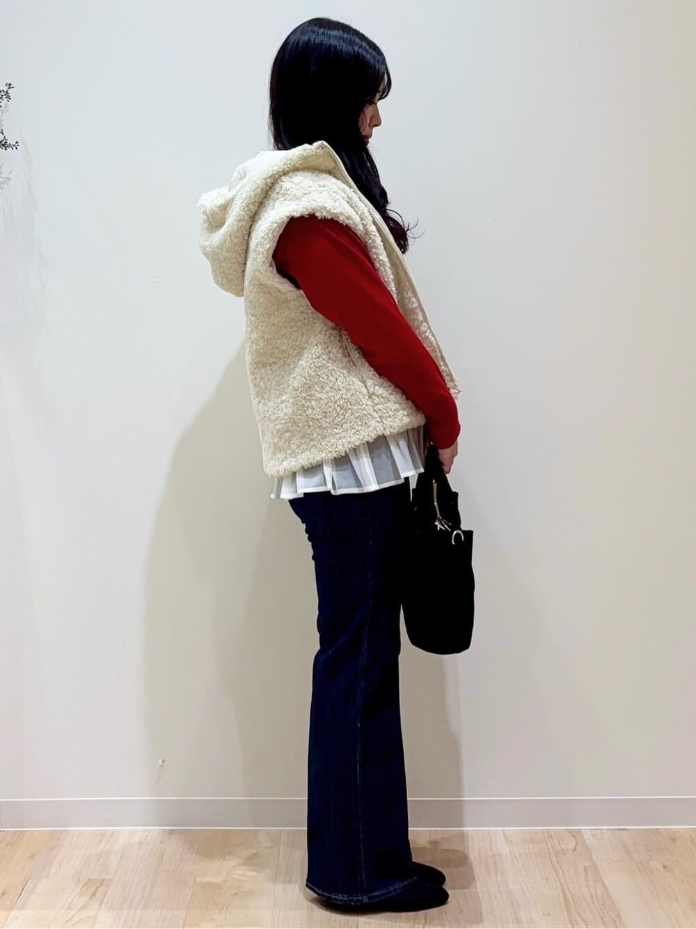 ホワイト系のブルゾン、レッド系のニット/セーター、ブルー系のデニムパンツを着用したレディースの秋コーディネートの2枚目の写真