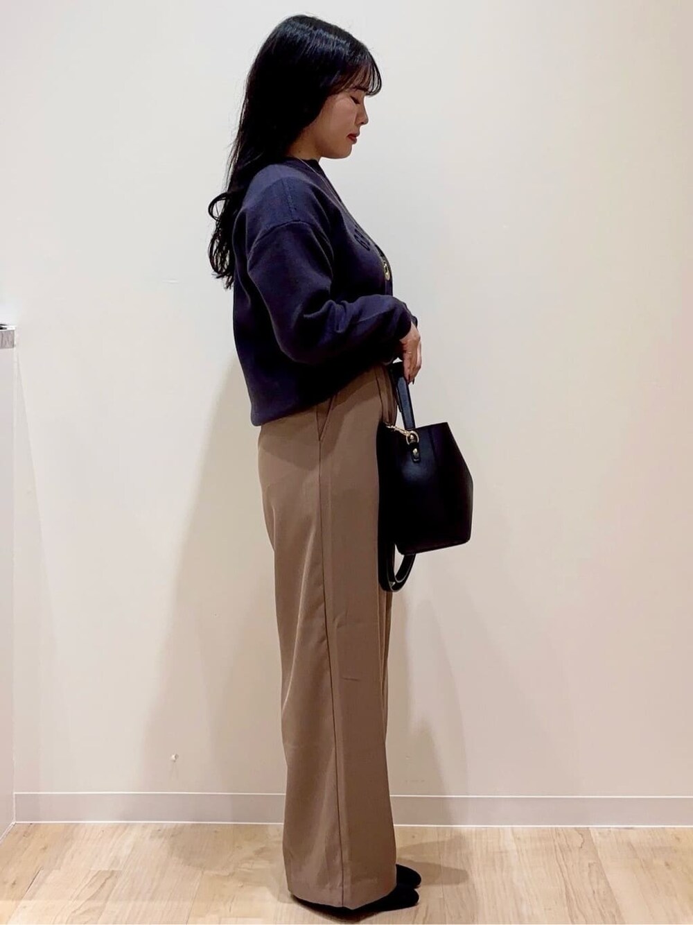 グレー系のニット/セーター、ブラウン系のその他パンツ、ブラック系のショルダーバッグを着用したレディースの秋コーディネートの2枚目の写真
