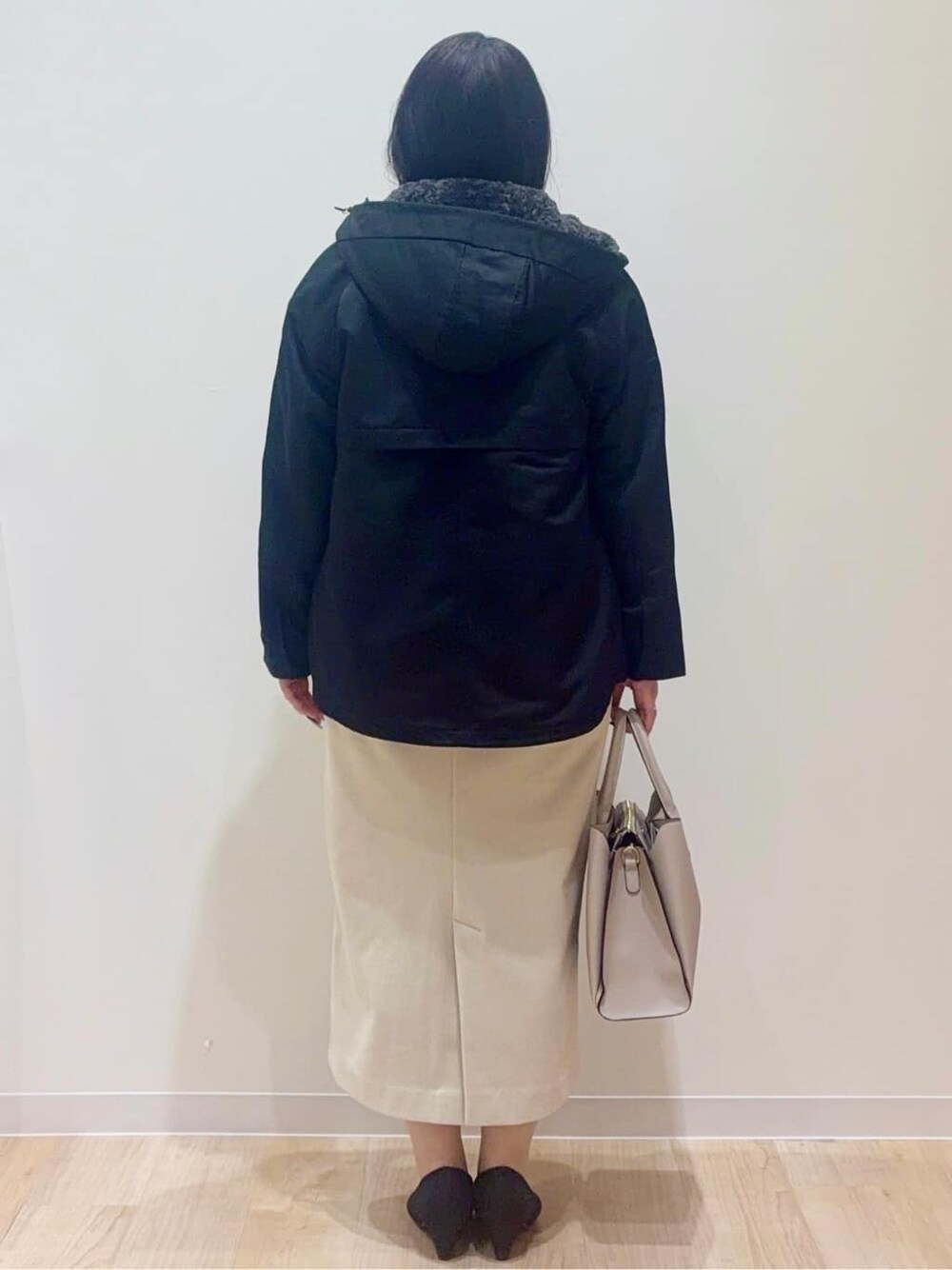 ブラック系のブルゾン、グレー系のニット/セーター、ベージュ系のスカートを着用したレディースの冬コーディネートの3枚目の写真