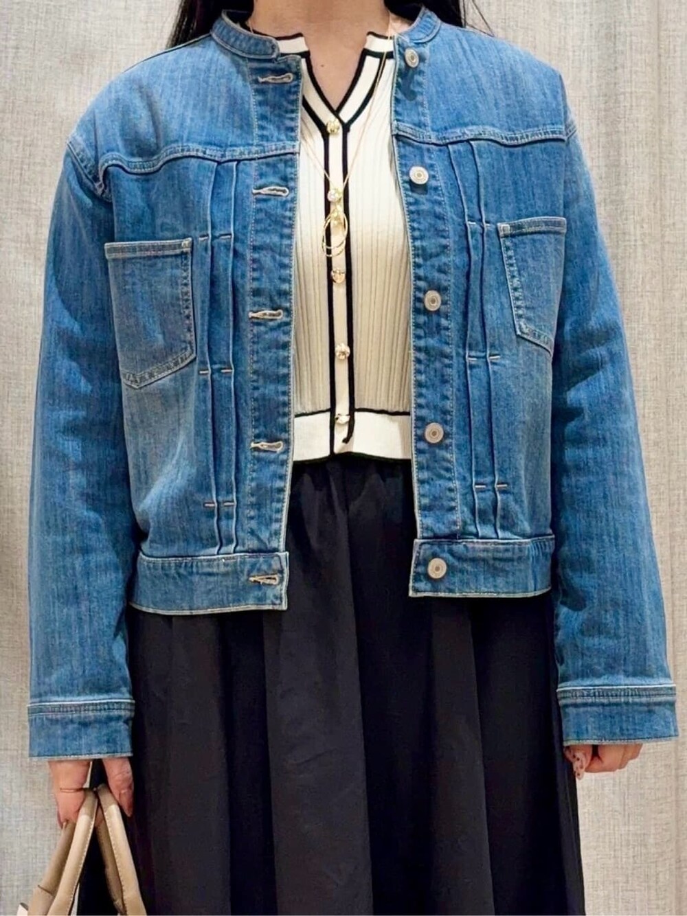 ブラック系のパンプス、ベージュ系のトートバッグ、ブルー系のデニムジャケットを着用したレディースの春コーディネートの4枚目の写真