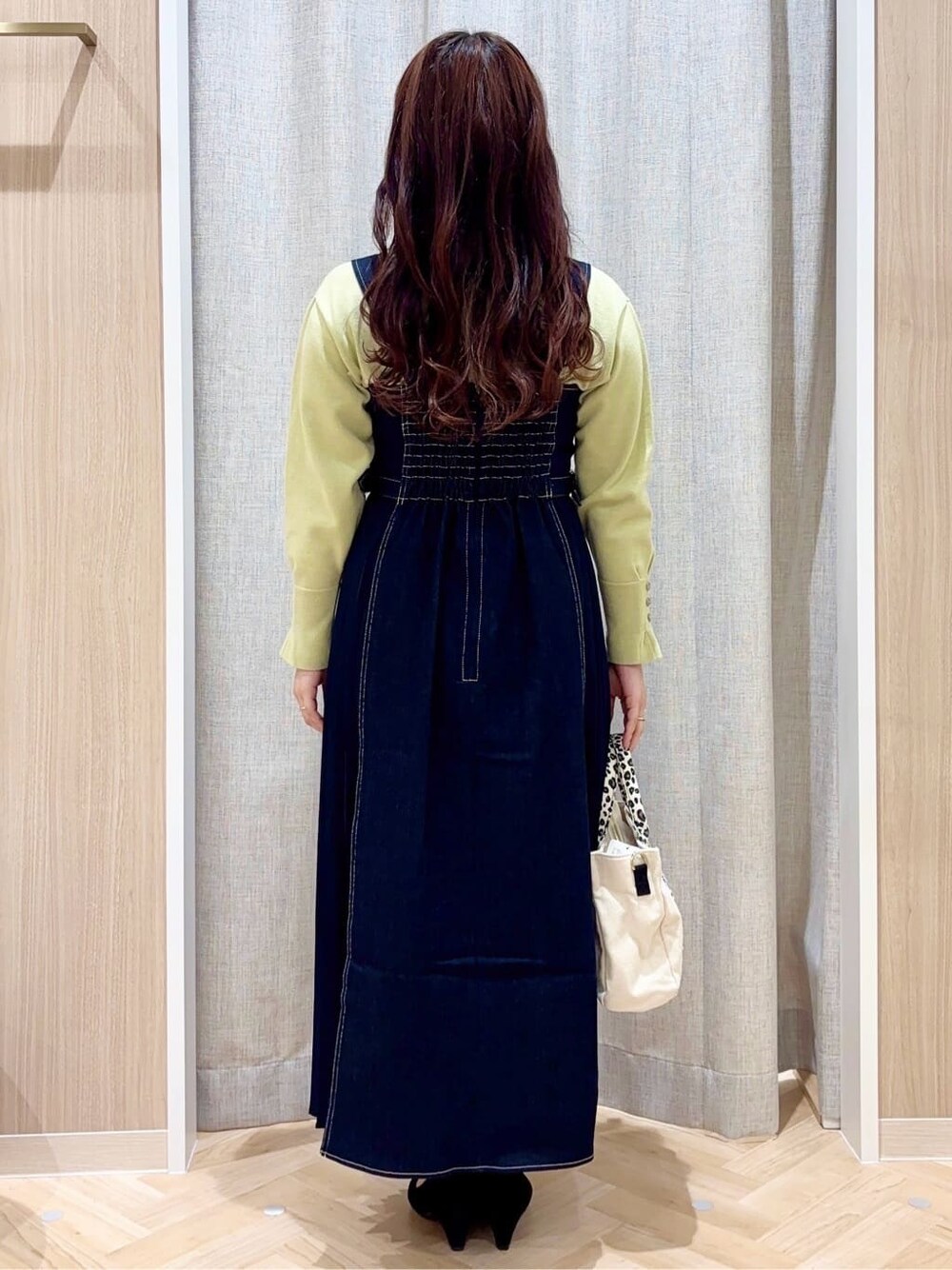 イエロー系のニット/セーター、ブルー系のワンピース、ベージュ系のトートバッグを着用したレディースの冬コーディネートの3枚目の写真