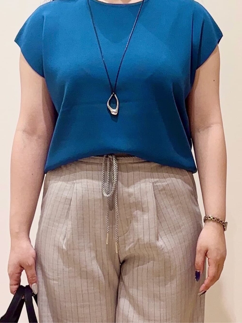 グレー系のその他パンツ、ブラック系のトートバッグ、シルバー系のネックレスを着用したレディースの夏コーディネートの4枚目の写真