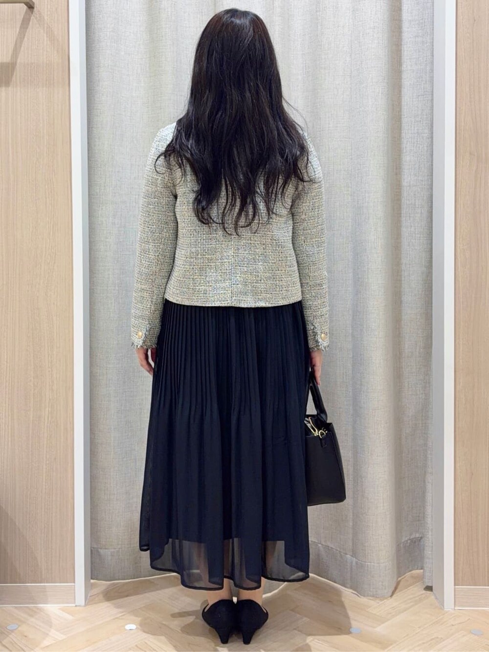 ブラック系のノーカラージャケット、ブラック系のワンピース、ブラック系のトートバッグを着用したレディースの冬コーディネートの3枚目の写真
