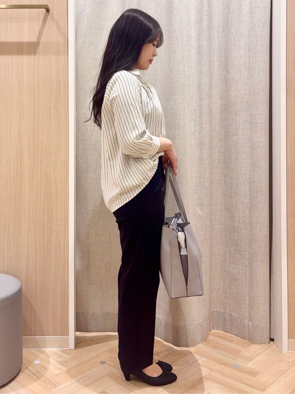 ブラック系のパンプス、ブルー系のトートバッグ、ブラック系のワンピースを着用したレディースの春コーディネートの2枚目の写真