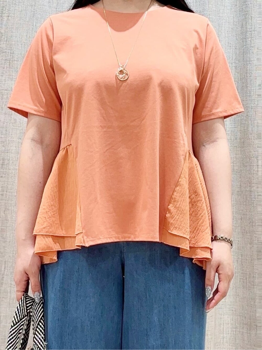 オレンジ系のTシャツ/カットソー、ベージュ系のトートバッグ、その他のネックレスを着用したレディースの夏コーディネートの4枚目の写真