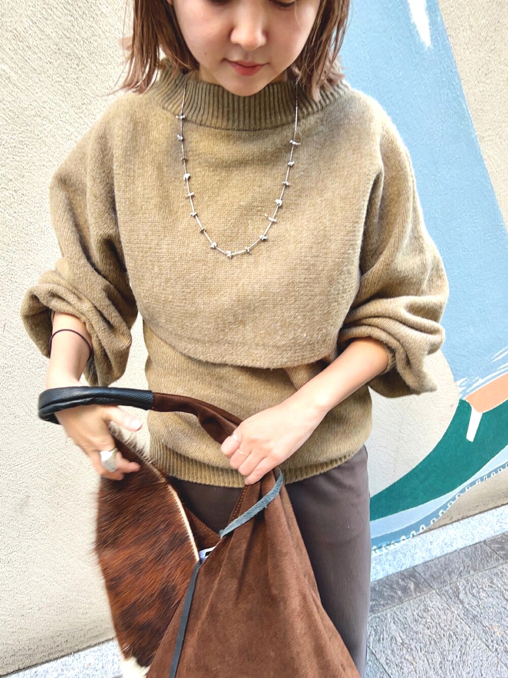 グリーン系のニット/セーターを着用したレディースの秋コーディネートの2枚目の写真