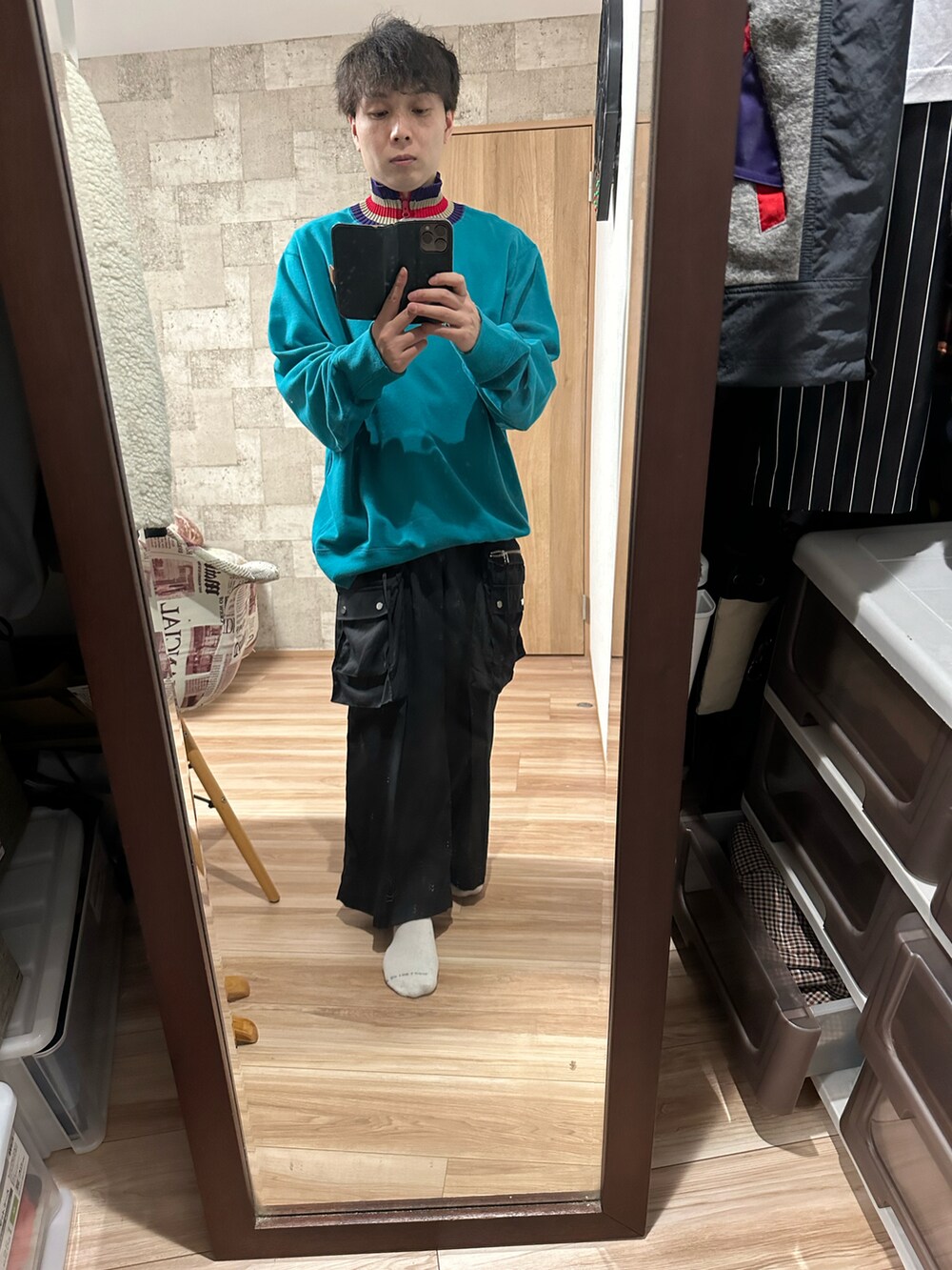 グリーン系のスウェット、ブラック系のカーゴパンツ、グレー系のダウンベストを着用したメンズの秋コーディネートの2枚目の写真