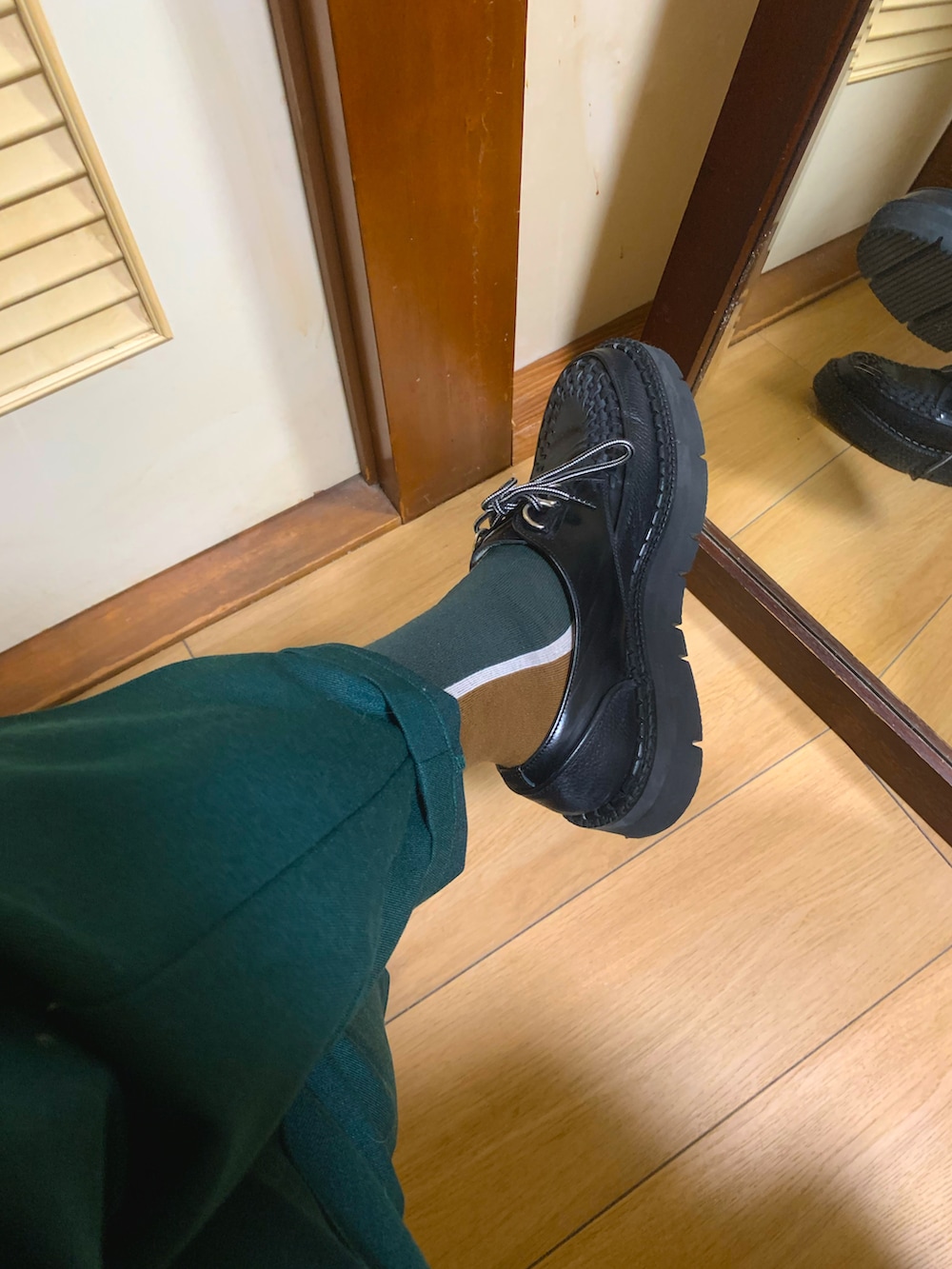 ベージュ系のトレンチコート、グリーン系のスラックス、ブラック系のドレスシューズを着用したメンズの冬コーディネートの2枚目の写真