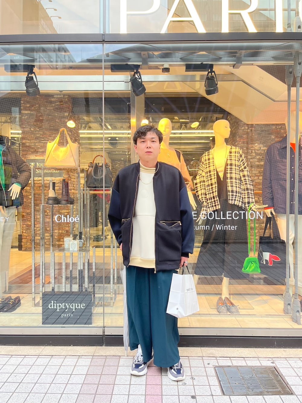 ブラック系のブルゾン、グレー系のスニーカー、ベージュ系のTシャツ/カットソーを着用したメンズの秋コーディネートの2枚目の写真