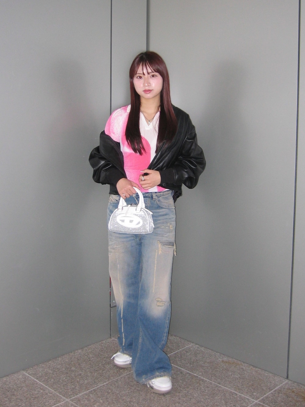 ブラック系のブルゾン、ホワイト系のスニーカー、ブルー系のデニムパンツを着用したレディースの春コーディネートの2枚目の写真