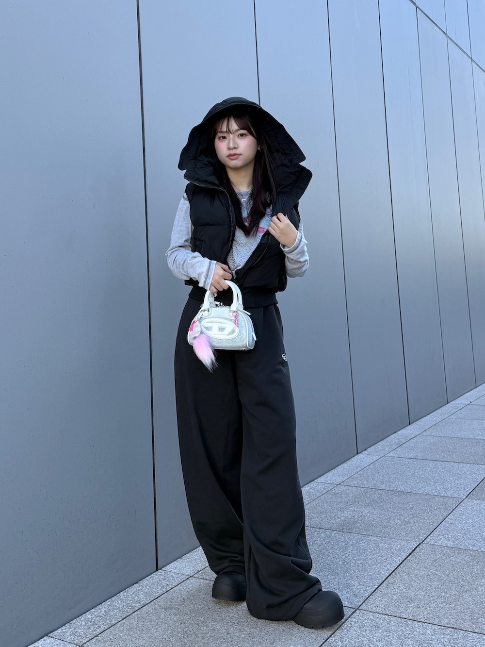 ブラック系のダウンベスト、グレー系のTシャツ/カットソー、ブラック系のスウェットパンツを着用したレディースの冬コーディネートの3枚目の写真