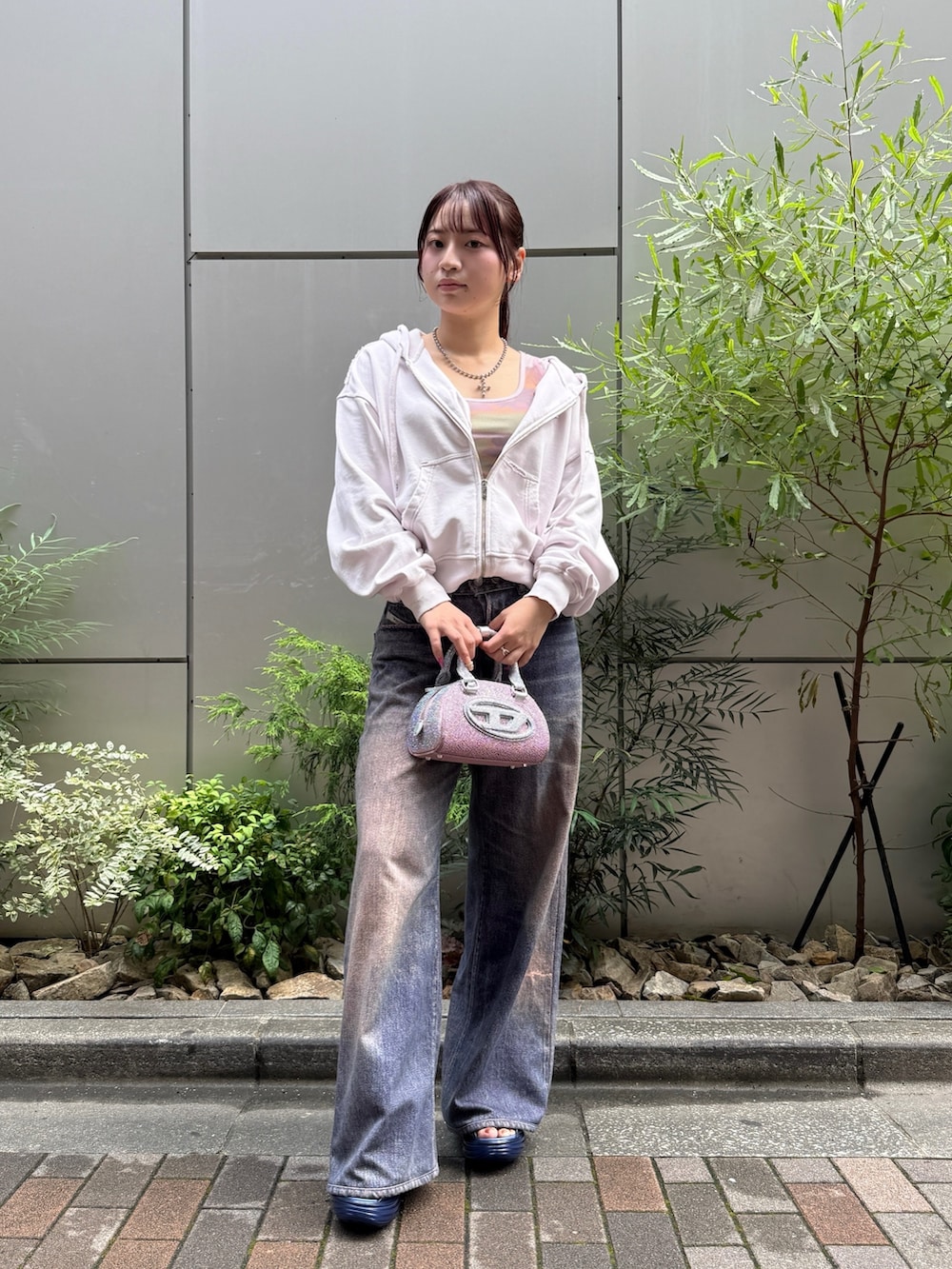 ピンク系のショルダーバッグ、パープル系のTシャツ/カットソー、パープル系のデニムパンツを着用したレディースの夏コーディネートの2枚目の写真