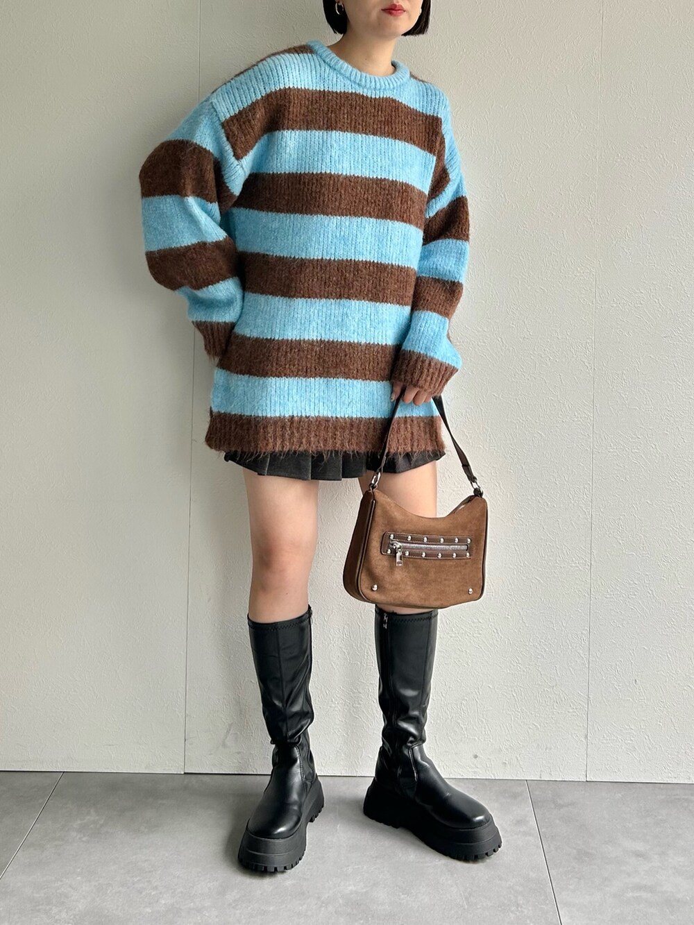 ブルー系のニット/セーター、ブラウン系のハンドバッグを着用したレディースの秋コーディネートの2枚目の写真
