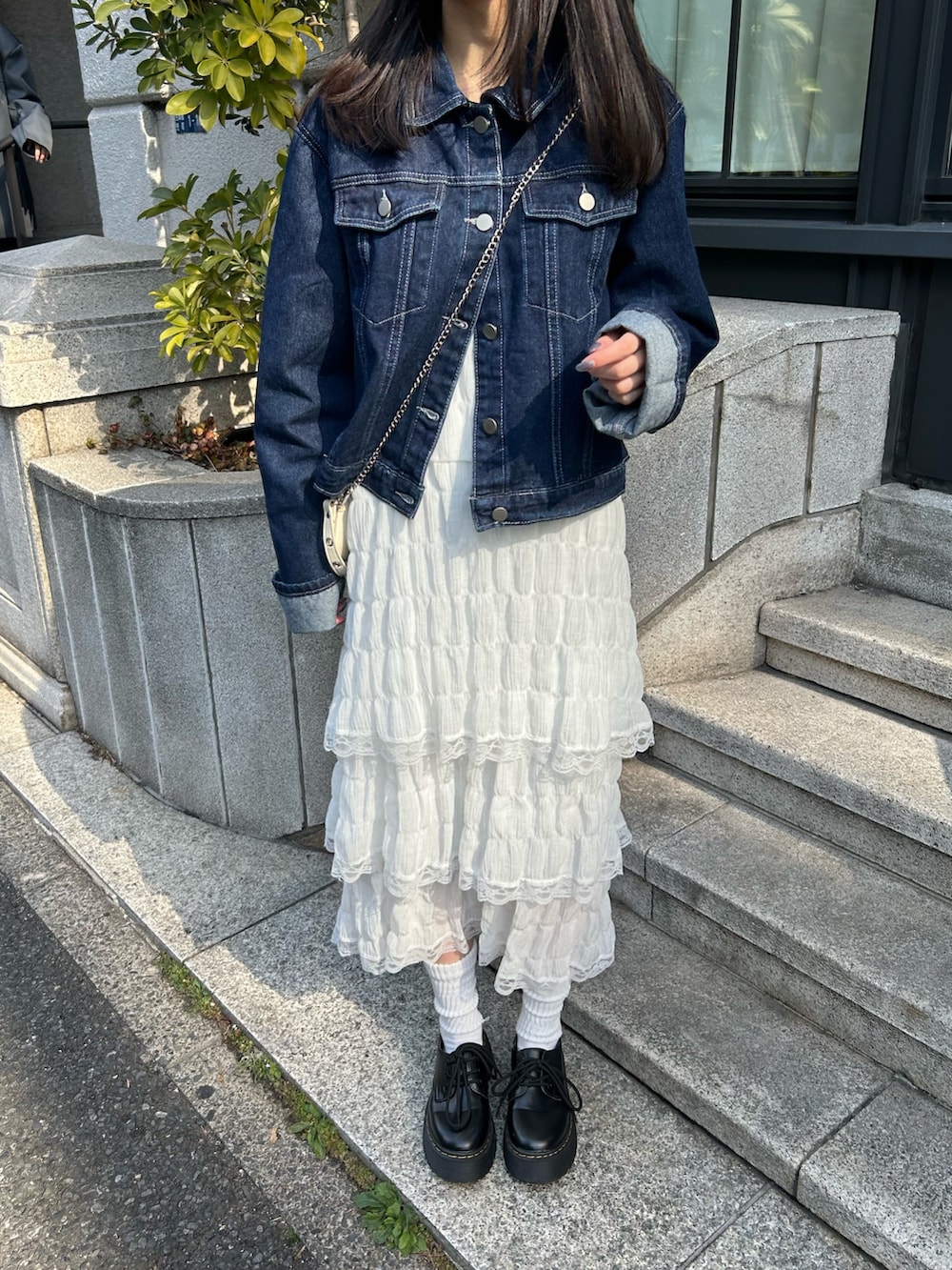 ブルー系のデニムジャケット、ホワイト系のワンピース、ブラック系のドレスシューズを着用したレディースの春コーディネートの2枚目の写真