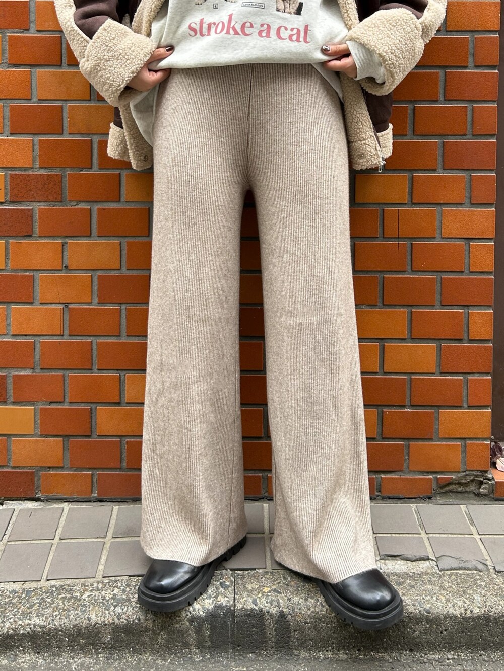 ブラウン系のムートンコート、ベージュ系のスウェット、ベージュ系のその他パンツを着用したレディースの冬コーディネートの2枚目の写真