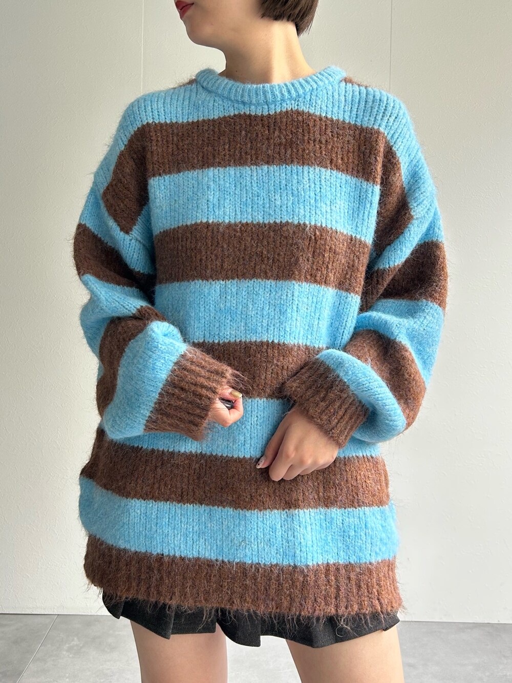 ブルー系のニット/セーター、ブラウン系のハンドバッグを着用したレディースの秋コーディネートの3枚目の写真