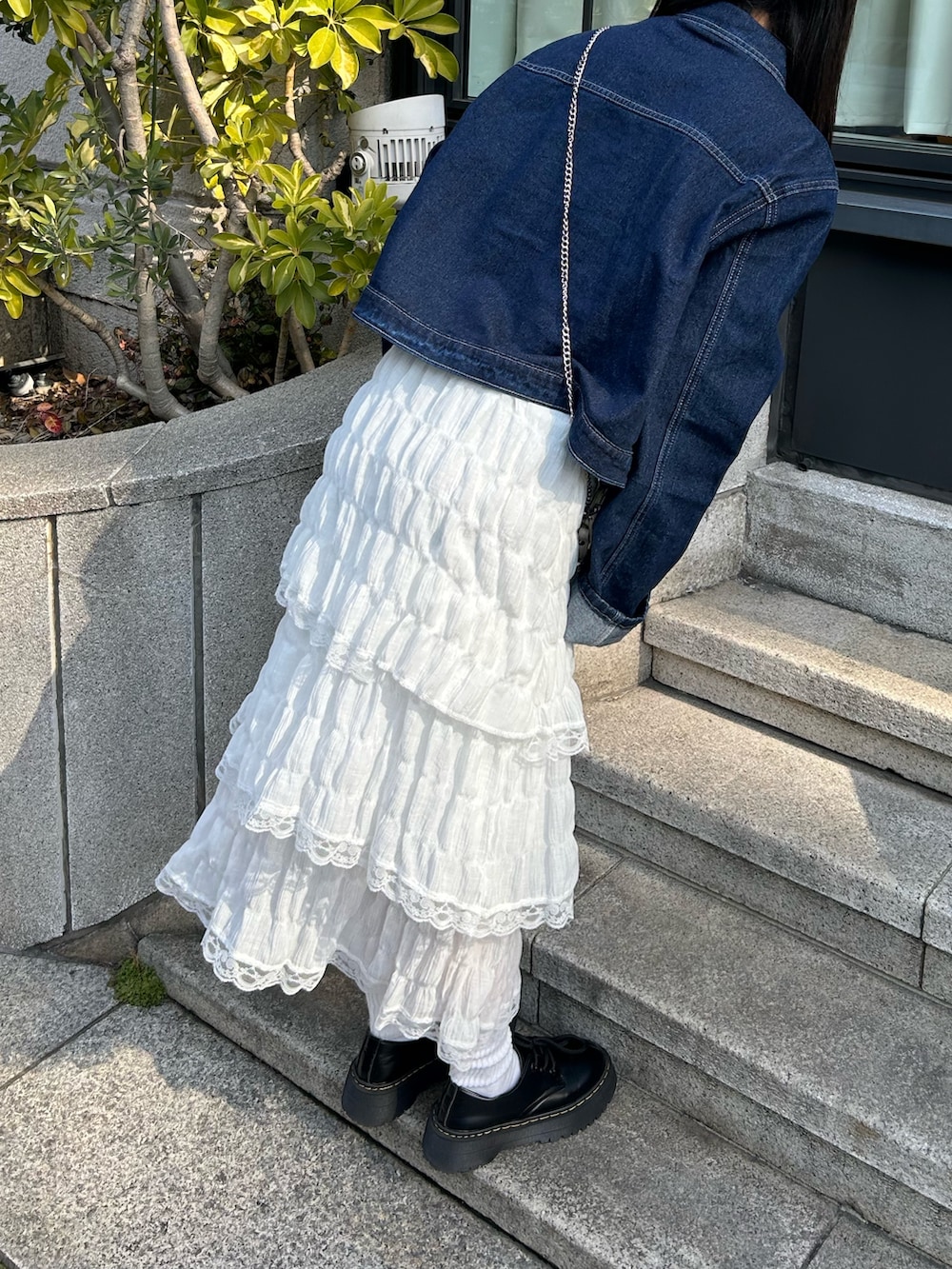 ブルー系のデニムジャケット、ホワイト系のワンピース、ブラック系のドレスシューズを着用したレディースの春コーディネートの3枚目の写真