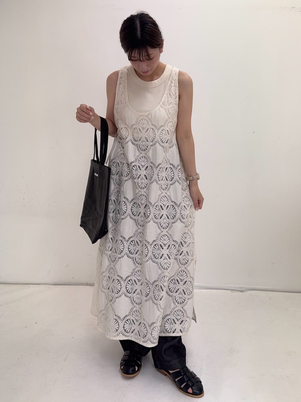 ベージュ系のワンピース、ブラック系のデニムパンツ、ブラック系のサンダルを着用したレディースの夏コーディネートの2枚目の写真