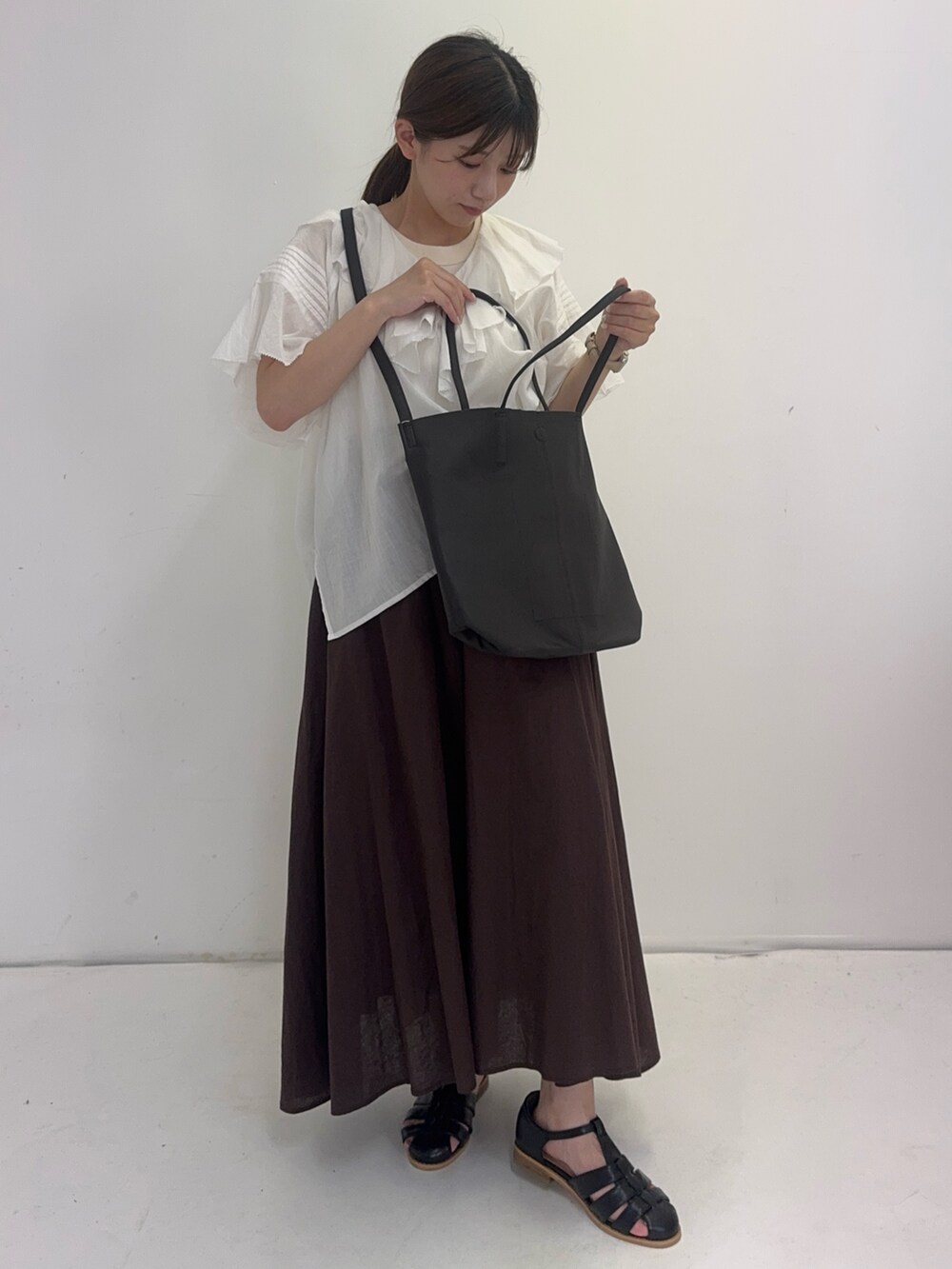 ホワイト系のシャツ/ブラウス、ブラウン系のスカート、ブラック系のサンダルを着用したレディースの夏コーディネートの3枚目の写真