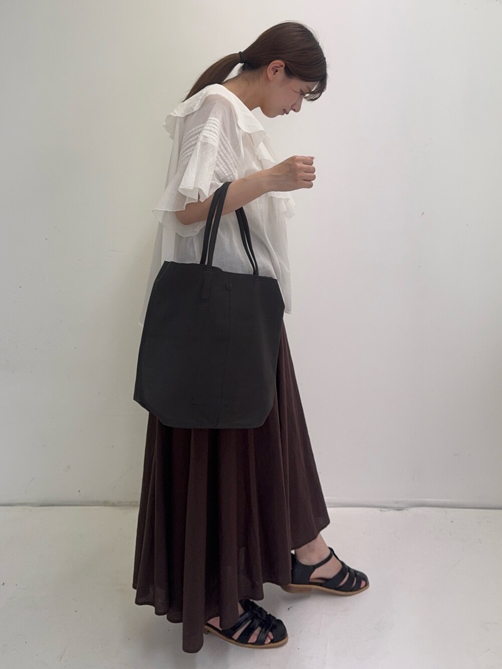 ホワイト系のシャツ/ブラウス、ブラウン系のスカート、ブラック系のサンダルを着用したレディースの夏コーディネートの4枚目の写真