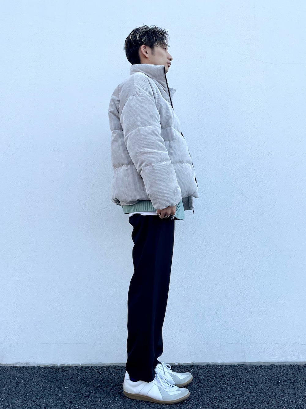 ベージュ系のダウンジャケット/コート、グリーン系のニット/セーター、ブラック系のスラックスを着用したメンズの冬コーディネートの2枚目の写真