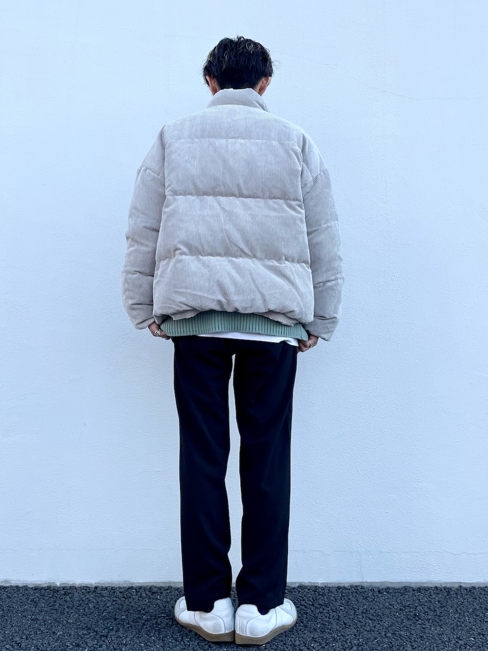 ベージュ系のダウンジャケット/コート、グリーン系のニット/セーター、ブラック系のスラックスを着用したメンズの冬コーディネートの3枚目の写真