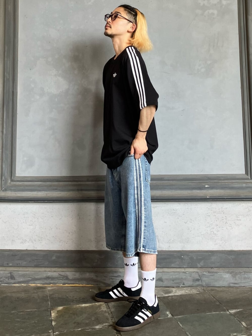 ブルー系のデニムパンツ、ブラック系のスニーカー、ブラック系のTシャツ/カットソーを着用したメンズの秋コーディネートの2枚目の写真