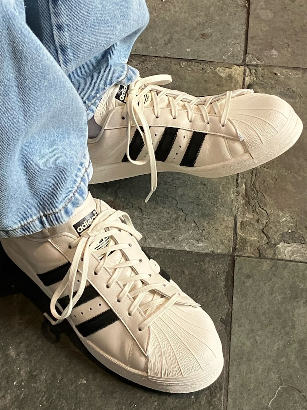 レッド系のジャージ、ブルー系のデニムパンツ、ホワイト系のスニーカーを着用したメンズの夏コーディネートの4枚目の写真