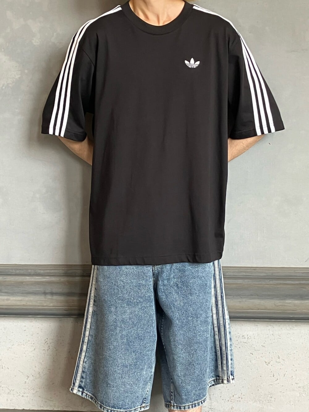 ブルー系のデニムパンツ、ブラック系のスニーカー、ブラック系のTシャツ/カットソーを着用したメンズの秋コーディネートの3枚目の写真