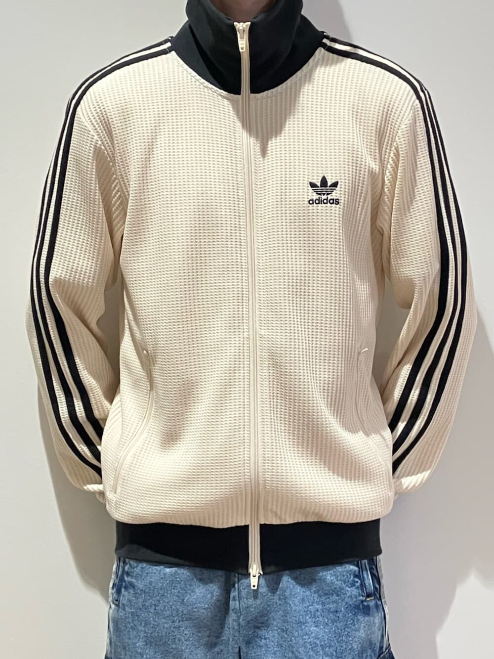 シルバー系のスニーカー、ホワイト系のジャージ、ブルー系のデニムパンツを着用したメンズの夏コーディネートの3枚目の写真