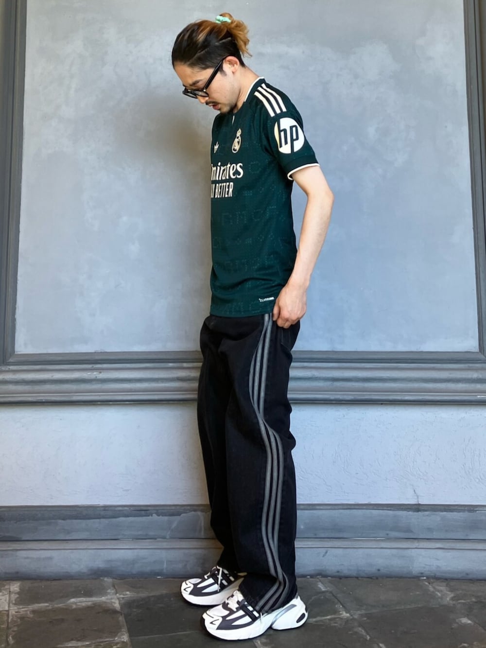 ブラック系のデニムパンツ、グリーン系のTシャツ/カットソー、グレー系のスニーカーを着用したメンズの夏コーディネートの2枚目の写真