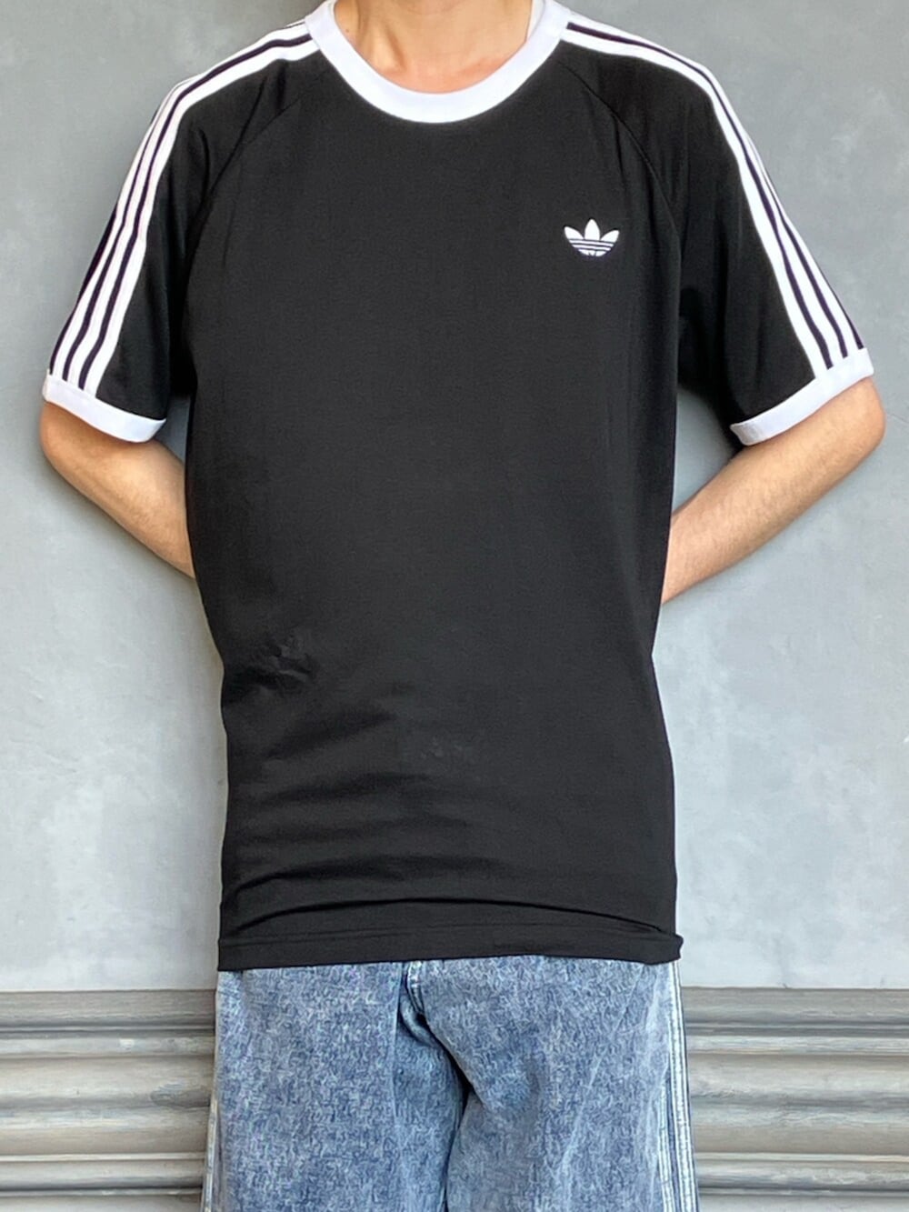ブラック系のTシャツ/カットソー、ブルー系のデニムパンツ、ホワイト系のスニーカーを着用したメンズの秋コーディネートの3枚目の写真