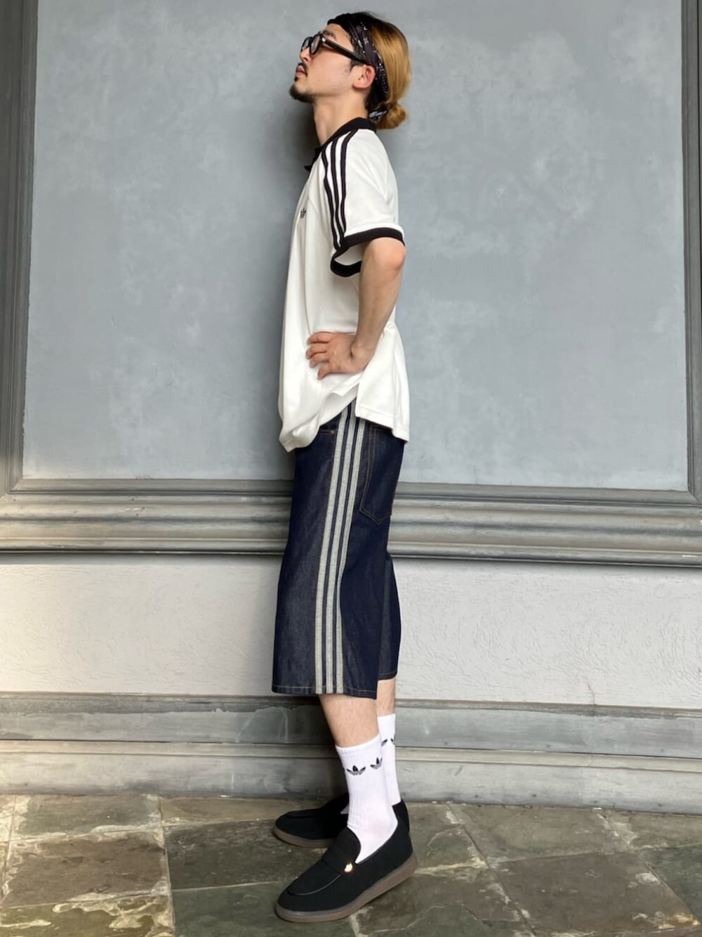ホワイト系のポロシャツ、ブルー系のデニムパンツ、ブラック系のローファーを着用したメンズの夏コーディネートの2枚目の写真