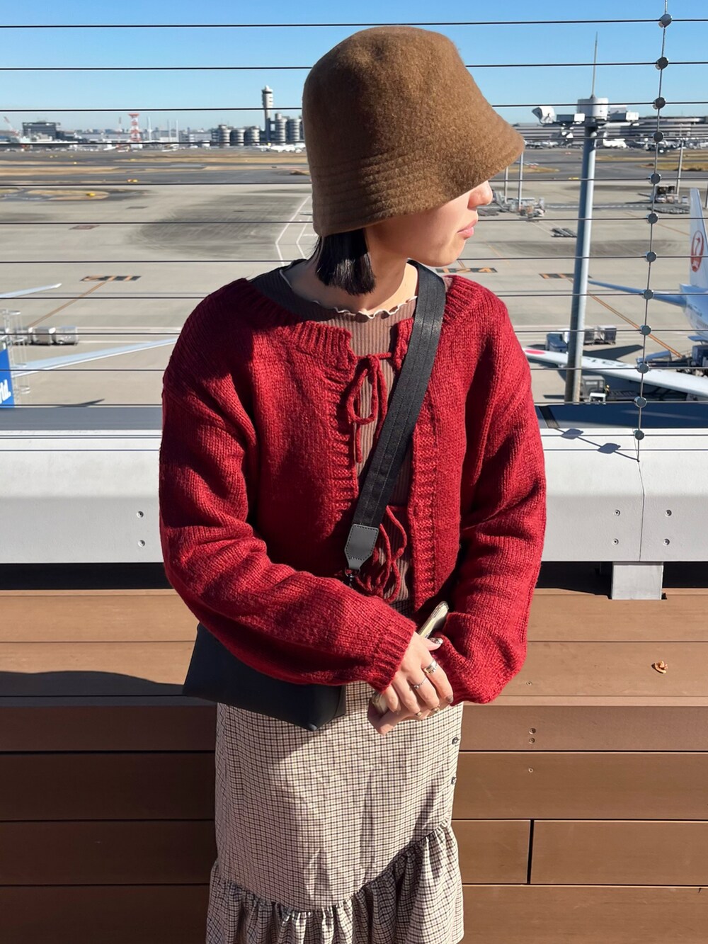 ブラック系のショルダーバッグ、レッド系のニット/セーター、ベージュ系のスカートを着用したレディースの冬コーディネートの2枚目の写真