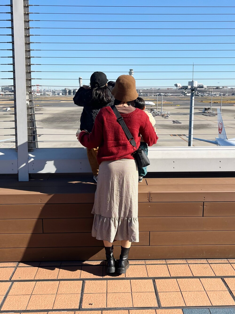 ブラック系のショルダーバッグ、レッド系のニット/セーター、ベージュ系のスカートを着用したレディースの冬コーディネートの3枚目の写真