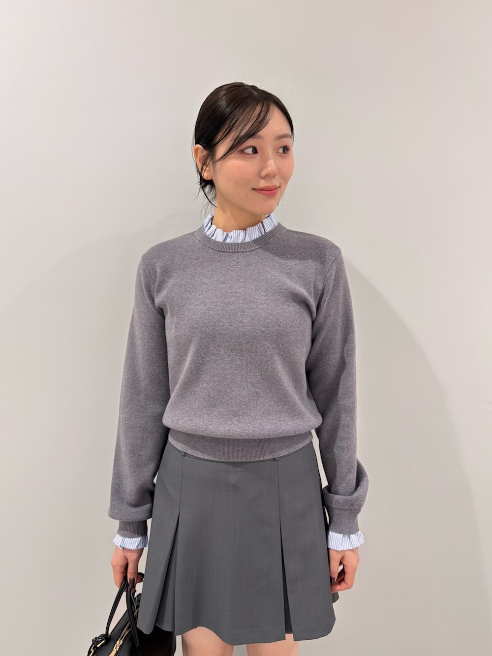 グレー系のニット/セーター、グレー系のスカート、ブラック系のボストンバッグを着用したレディースの秋コーディネートの5枚目の写真