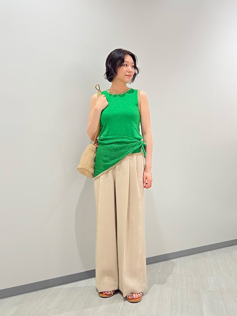 グリーン系のニット/セーター、ベージュ系のパンツ、ベージュ系のショルダーバッグを着用したレディースの夏コーディネートの3枚目の写真