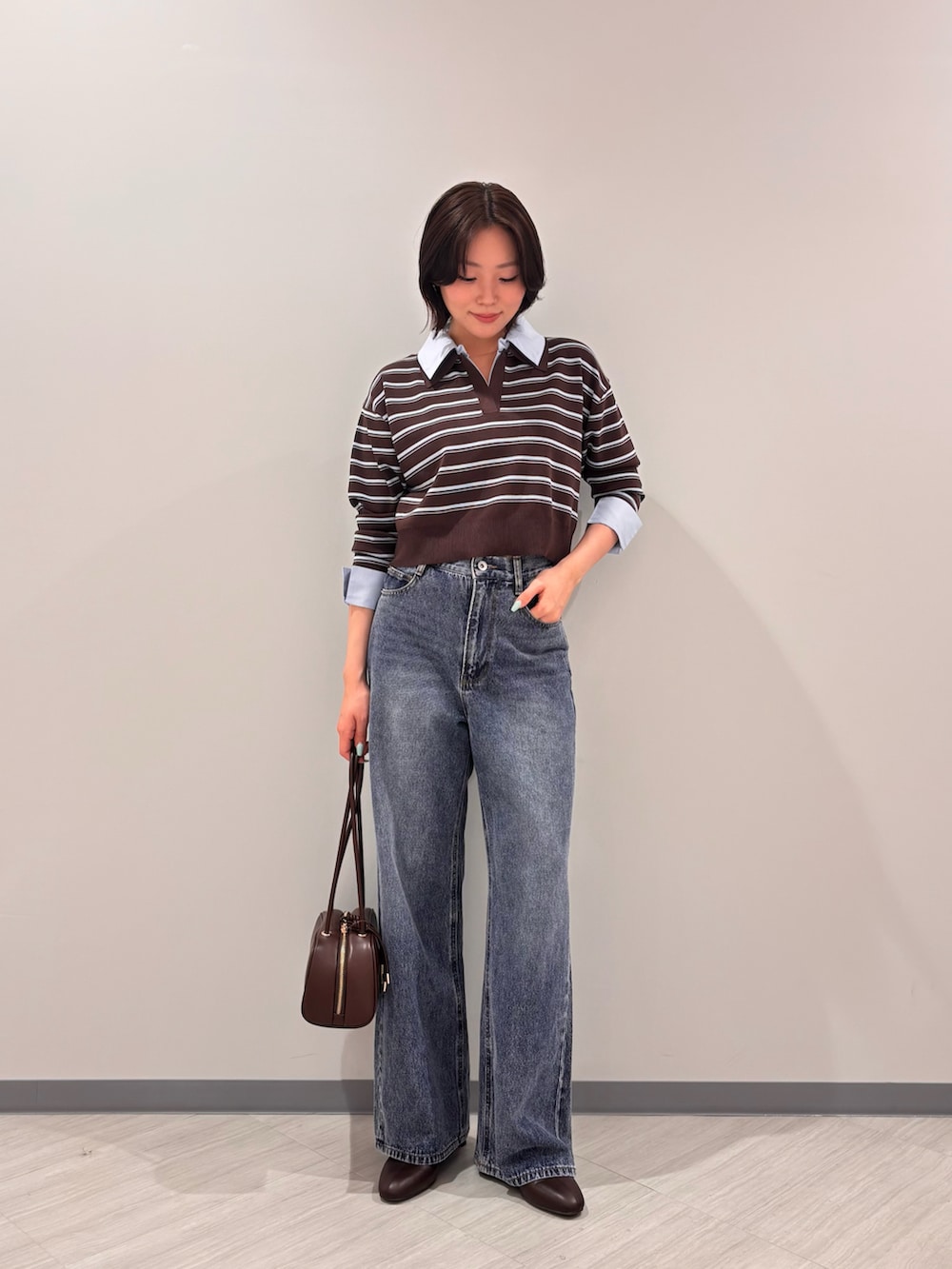 ブラウン系のニット/セーター、ブルー系のデニムパンツ、ブラック系のボストンバッグを着用したレディースの秋コーディネートの4枚目の写真