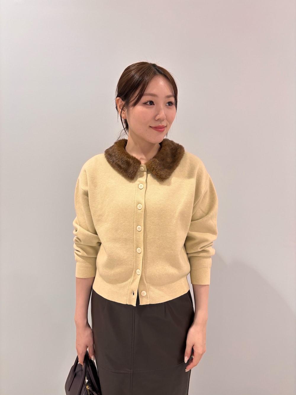 イエロー系のカーディガン/ボレロ、ブラウン系のスカート、ブラウン系のブーツを着用したレディースの秋コーディネートの4枚目の写真