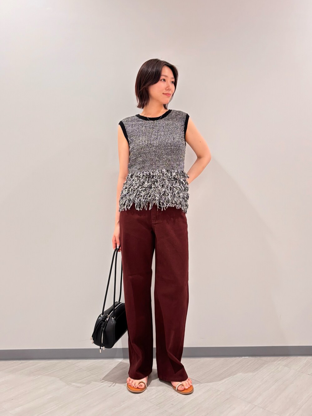 ブラック系のニット/セーター、ブラウン系のその他パンツ、イエロー系のサンダルを着用したレディースの夏コーディネートの2枚目の写真