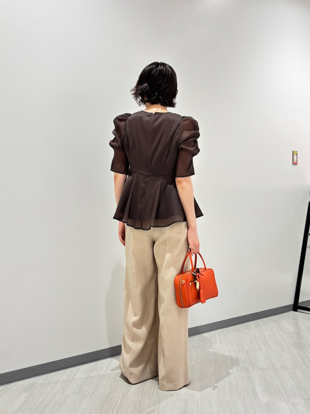 ブラウン系のシャツ/ブラウス、ベージュ系のパンツ、オレンジ系のボストンバッグを着用したレディースの夏コーディネートの5枚目の写真