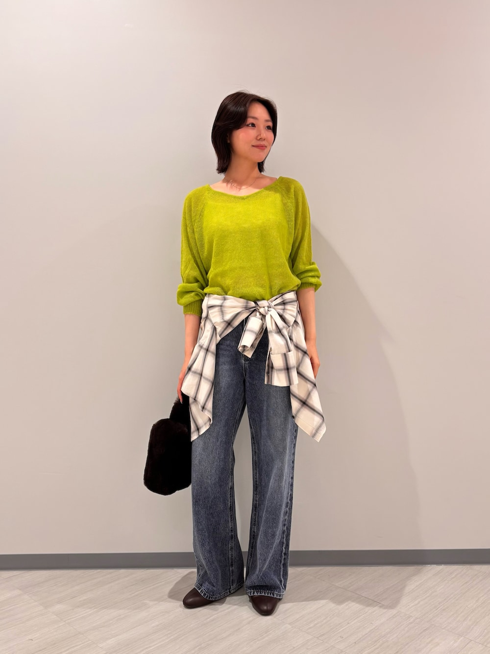 グリーン系のニット/セーター、ホワイト系のシャツ/ブラウス、ブルー系のデニムパンツを着用したレディースの秋コーディネートの3枚目の写真