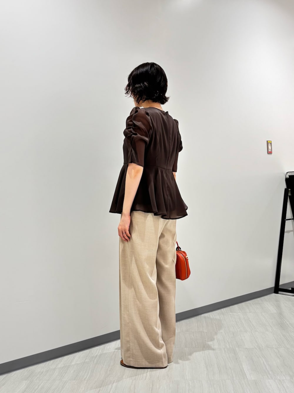 ブラウン系のシャツ/ブラウス、ベージュ系のパンツ、オレンジ系のボストンバッグを着用したレディースの夏コーディネートの4枚目の写真