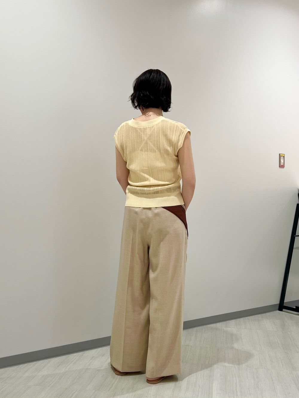 ベージュ系のショルダーバッグ、イエロー系のニット/セーター、ベージュ系のパンツを着用したレディースの夏コーディネートの4枚目の写真