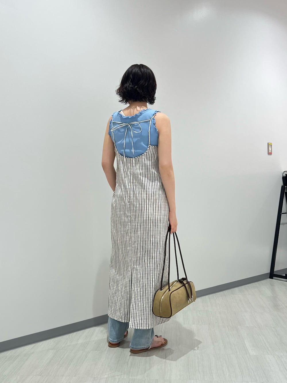 ブルー系のタンクトップ、ブルー系のデニムパンツ、ホワイト系のワンピースを着用したレディースの夏コーディネートの4枚目の写真